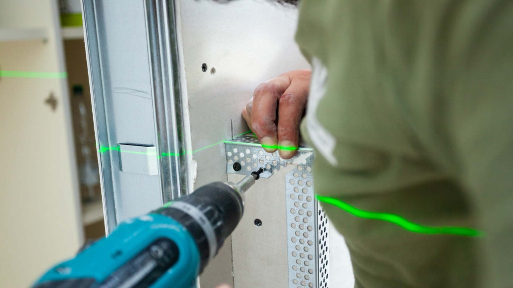 Worker building plasterboard wall. Working with cutting tools, fixing and measuring for drywall.