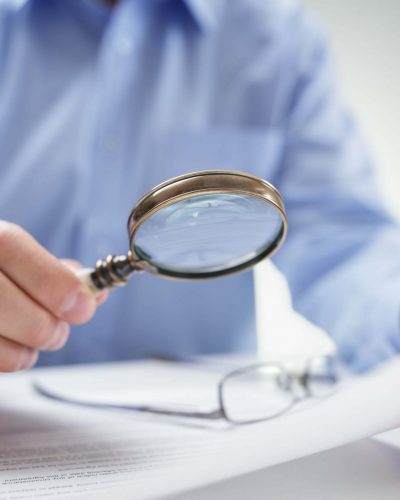 Businessman reading documents with magnifying glass concept for analyzing a finance agreement or legal contract